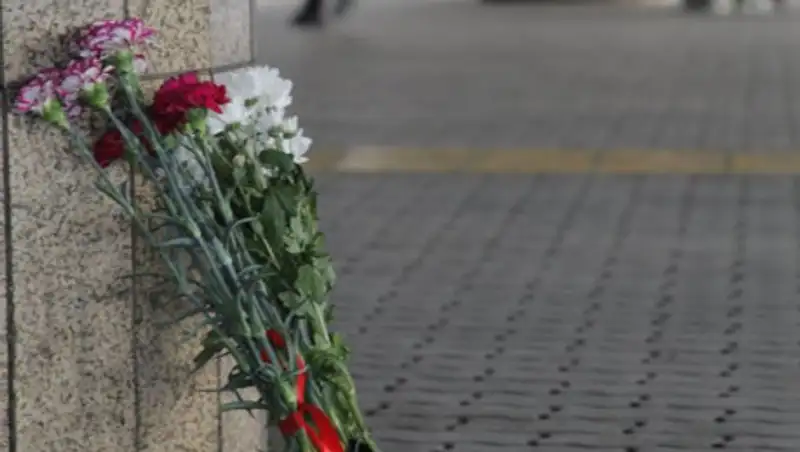 Люди с цветами идут к аэропорту Алматы