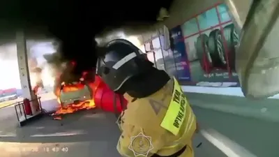 горящая машина на заправке в Актобе и тушащий ее пожарный, фото - Новости Zakon.kz от 21.07.2025 10:00
