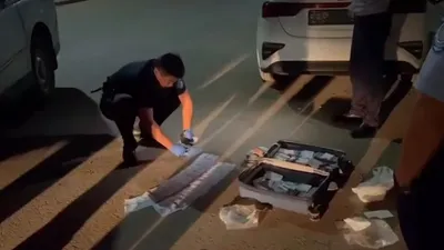 полицейский считает найденные в чемодане деньги, фото - Новости Zakon.kz от 21.08.2025 09:49