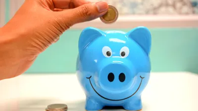 рука с монетой и копилка, фото - Новости Zakon.kz от 17.12.2025 10:39