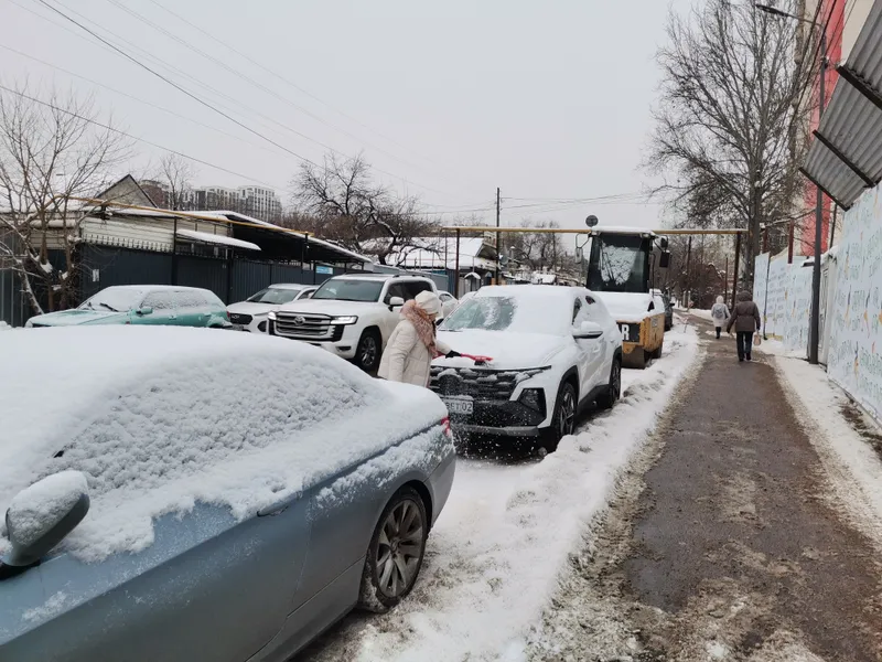 Девушка очищает машину от снега, фото - Новости Zakon.kz от 23.01.2026 10:24