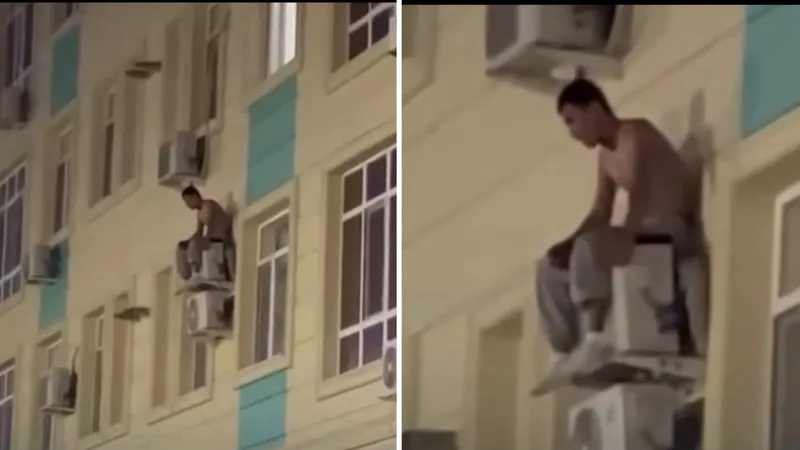Мужчина сидит на кондиционере, многоэтажный дом