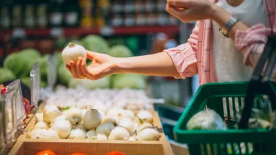 Женщина покупает в продуктовом магазине